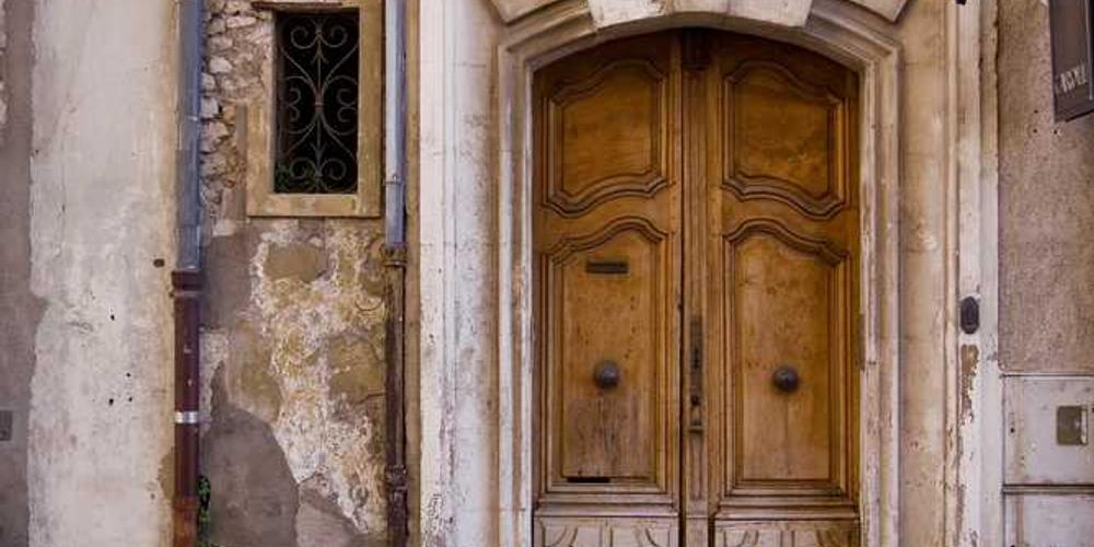 Alte Holztür in historischem Gebäude, kunstvoll gestaltet, Immobilienverwaltung Blog