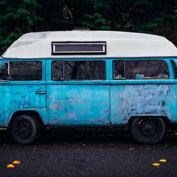 Alter blauer VW-Bus umgeben von Bäumen bei RentPilot