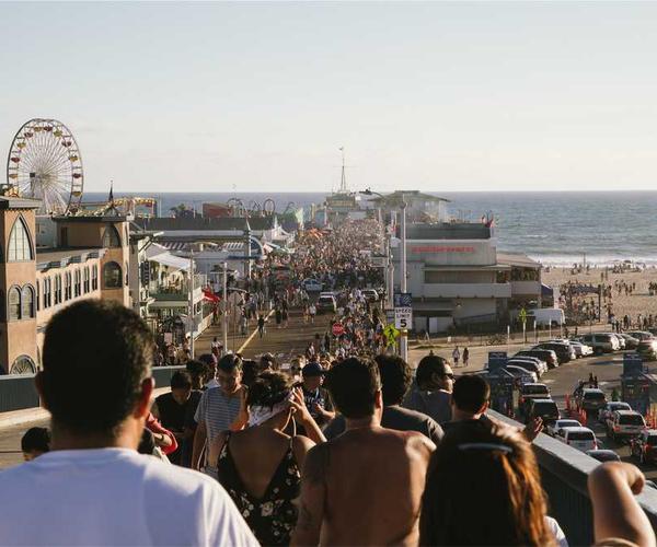 Belebte Küstenpromenade mit Menschen und Vergnügungspark, RentPilot