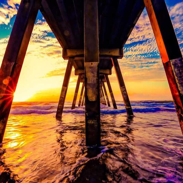 Farbenfroher Sonnenuntergang unter einem Pier - RentPilot