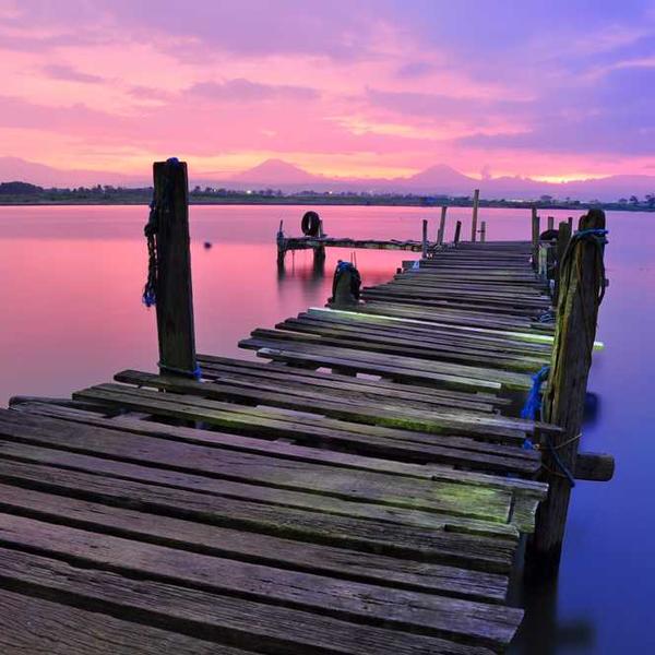 Holzsteg über ruhiges Wasser bei Sonnenuntergang – RentPilot