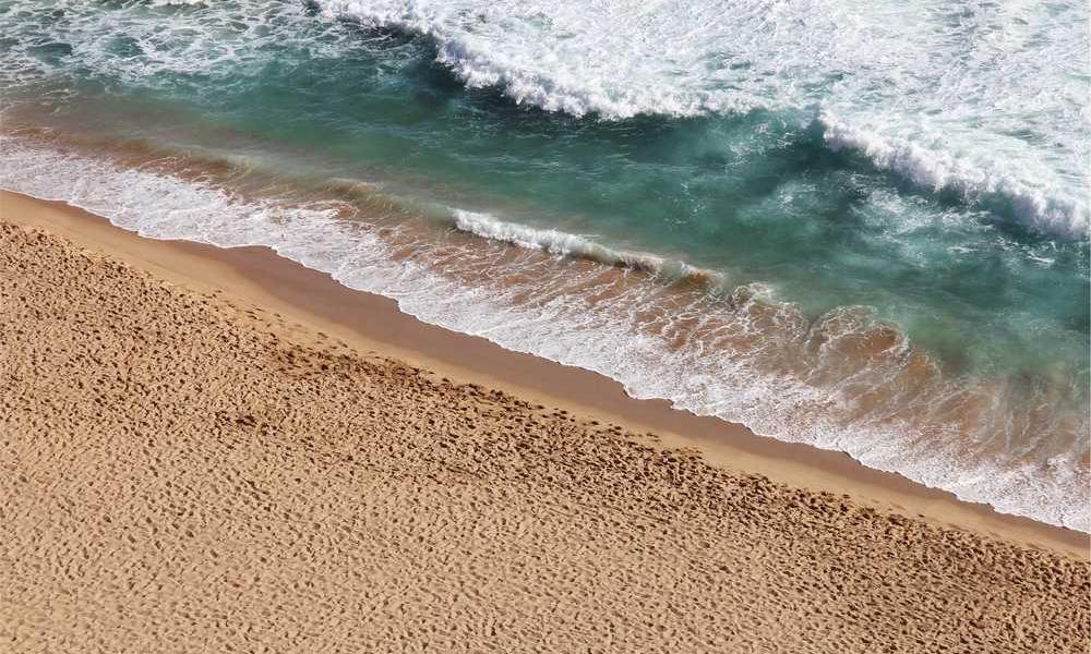 Küstenlandschaft mit Sandstrand und Wellen für Immobilienverwaltung Blog