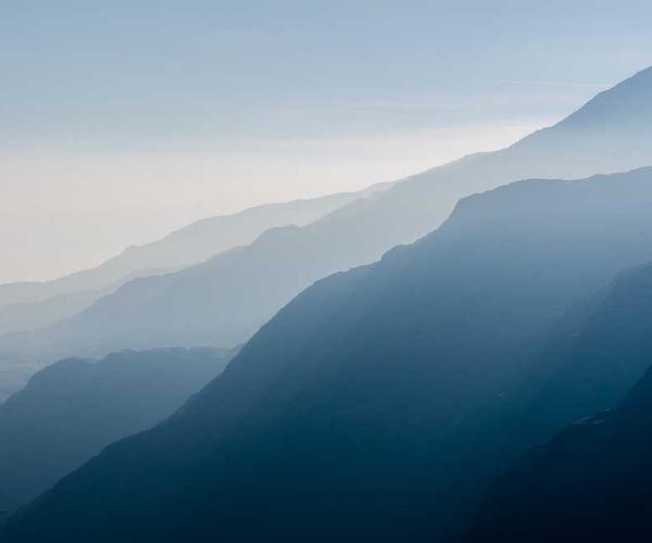 Landschaft mit sanften Hügeln und Bergen in Blautönen