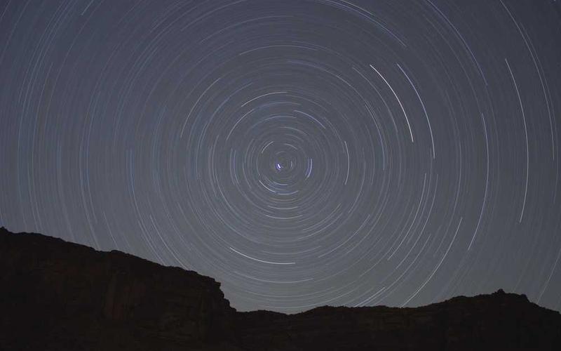 Langzeitbelichtung des Nachthimmels mit Sternenspuren.