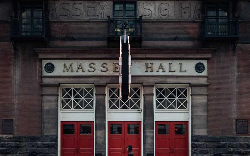 Fassade des Massey Hall mit roten Türen und historischer Architektur.