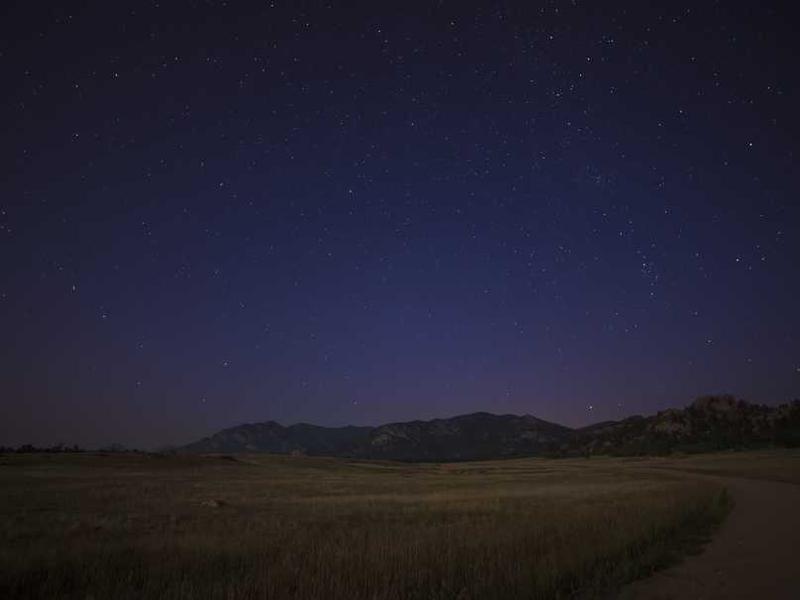 Nächtliche Landschaft mit Sternenhimmel über Feldern und Bergen – RentPilot