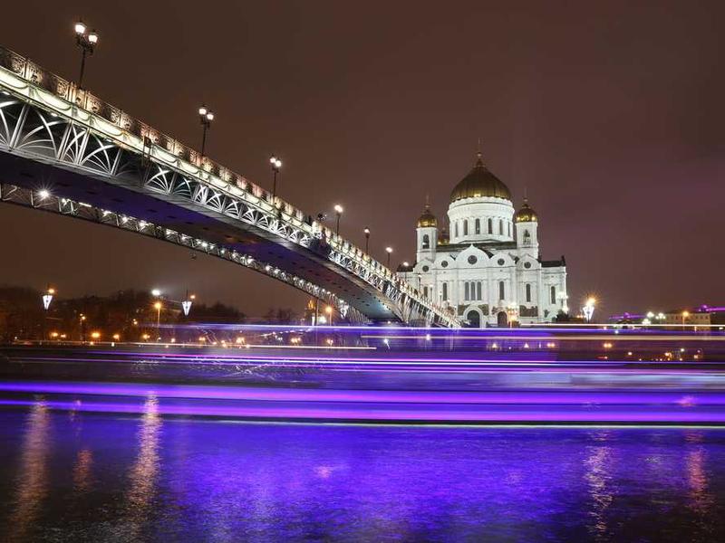 Nächtliche Stadtansicht mit beleuchteter Brücke und Kirche.
