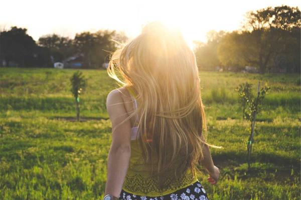Person mit langen Haaren in grüner Landschaft bei Sonnenlicht - RentPilot