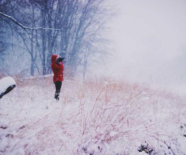 Person in rotem Mantel steht in winterlicher Landschaft – RentPilot Blog über Hausverwaltung