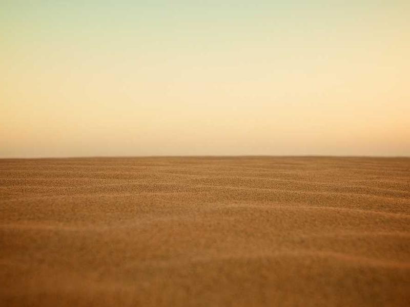 Abstrakte Darstellung einer sandigen Fläche unter einem farbigen Himmel für RentPilot