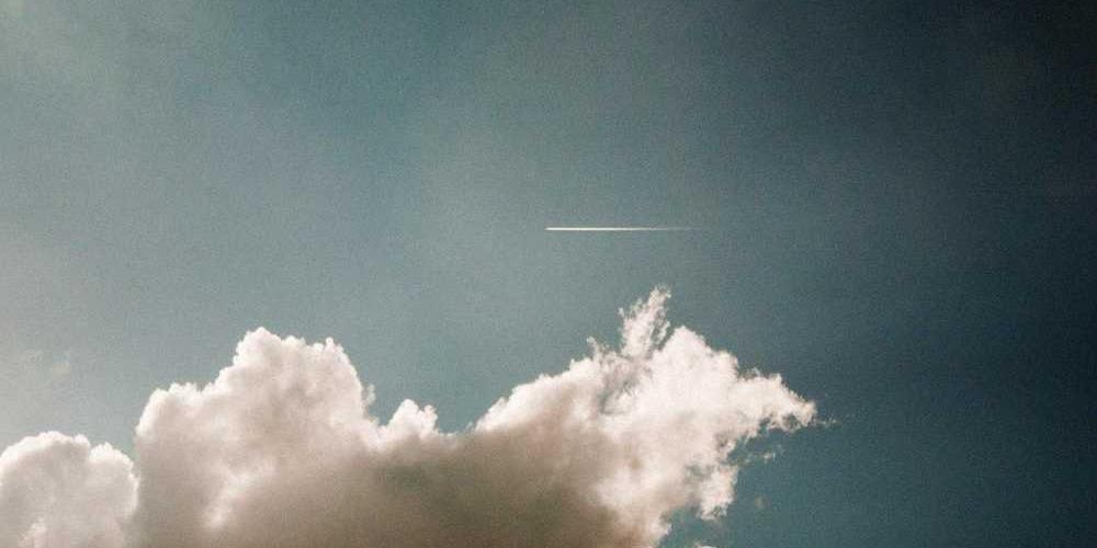 Wolkenlandschaft mit Flugzeug und Kondensstreifen
